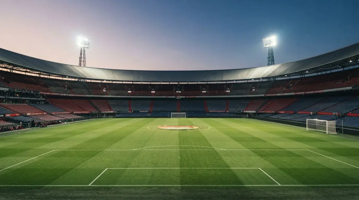 Een leeg voetbalstadion met lichtmasten bij schemering